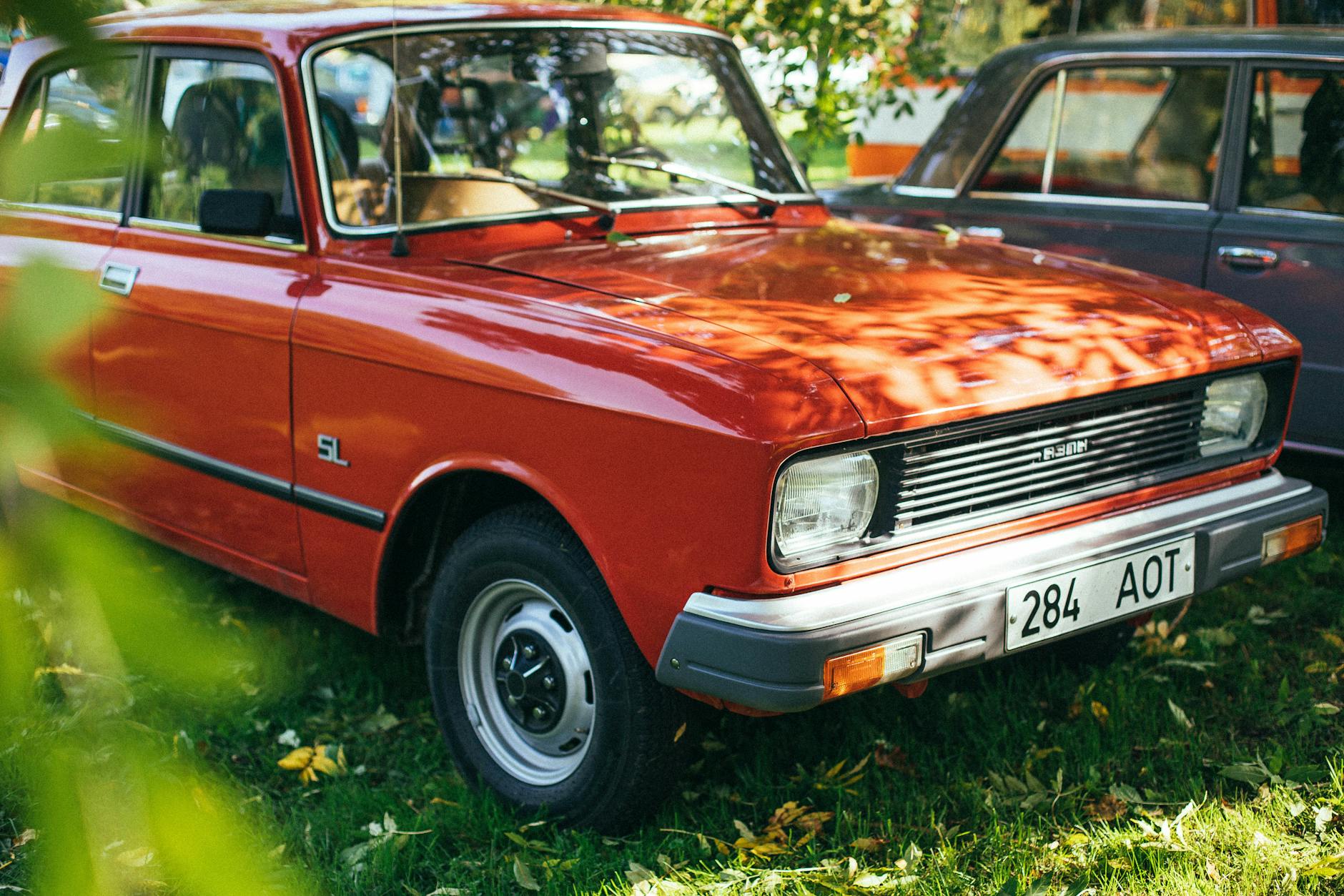Czerwone klasyczne auto z czasów PRL zaparkowane na zielonej trawie