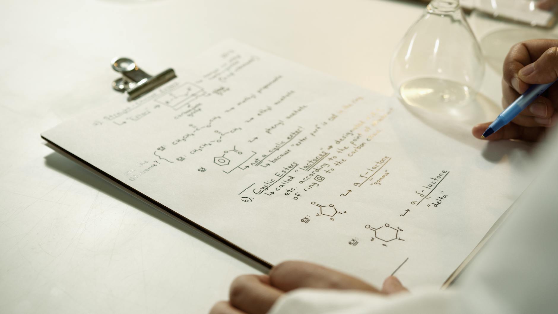 Zbliżenie notatek z wzorami chemicznymi na clipboardzie w laboratorium